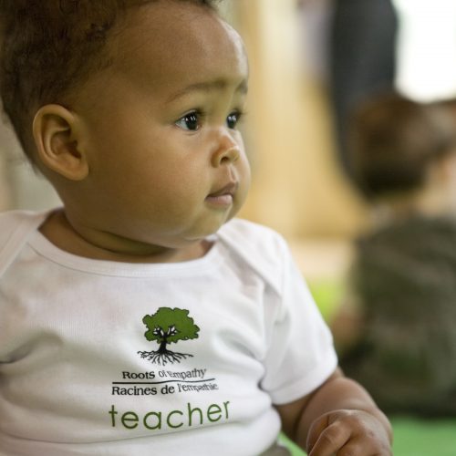a baby in a Roots of Empathy t shirt